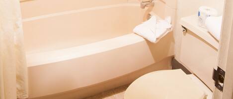 A bathroom with a bathtub, toilet, and a towel rack with folded towels.