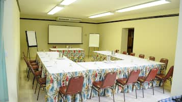 A conference room with a long table, chairs, a projector screen, and a whiteboard.