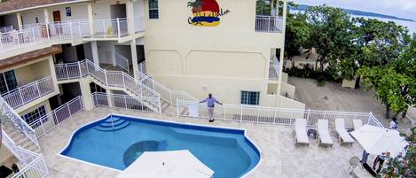 A hotel with a swimming pool, multiple balconies, and outdoor seating.
