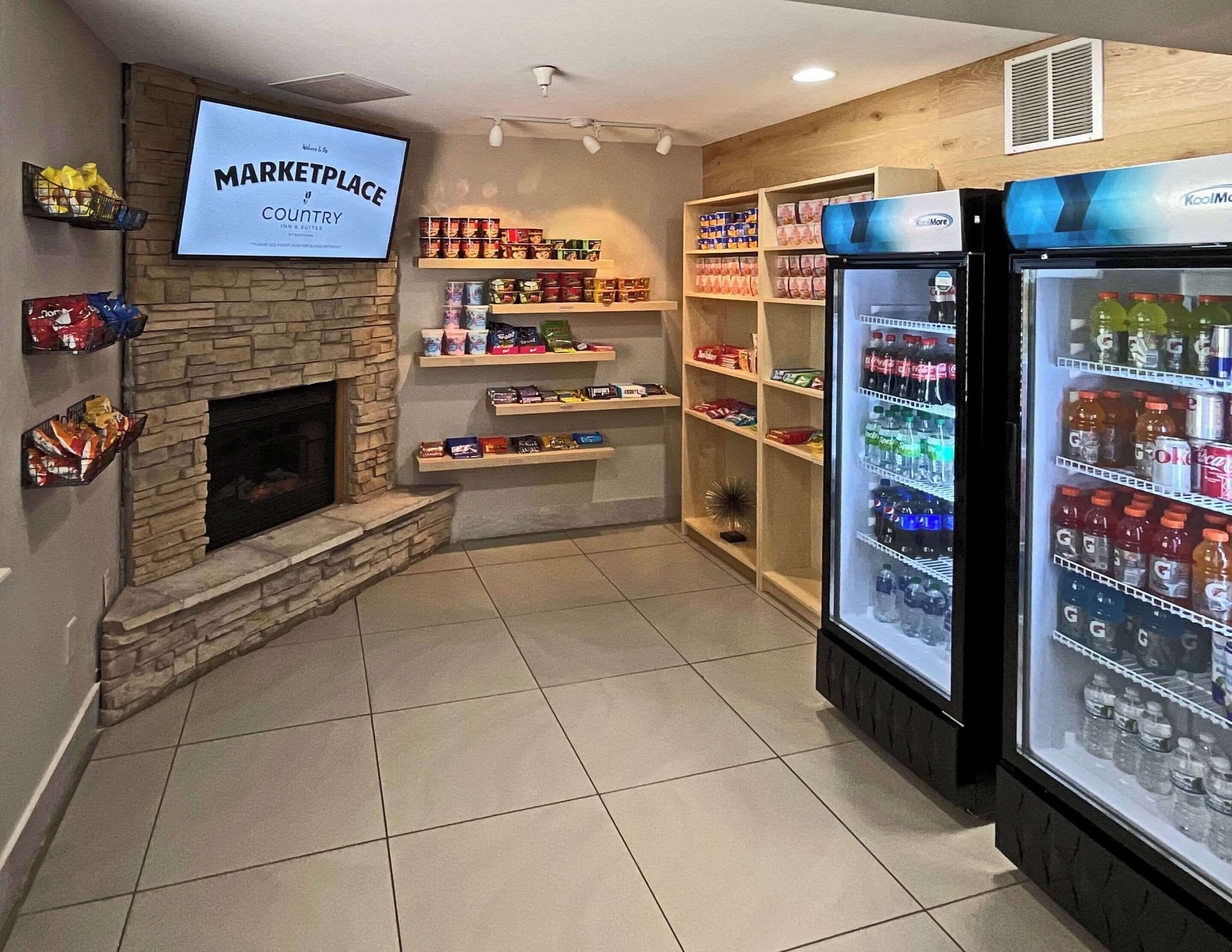 A kitchenette area with a stone fireplace, shelves stocked with snacks, and a refrigerator filled with beverages.
