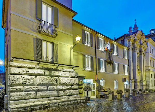 A historic building with a stone facade, multiple windows with shutters, and a sign for 'Hotel Indigo.'