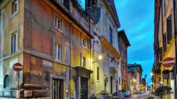 Una calle adoquinada flanqueada por edificios históricos, una señal de prohibido el paso y automóviles estacionados.