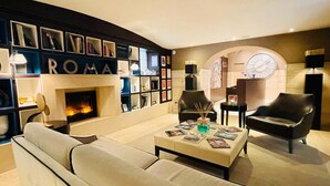A modern living room with a fireplace, bookshelves, a sofa, and two armchairs. - Hotel Indigo Rome - St. George by IHG (Rome)