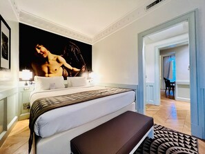 A hotel room with a large bed, bedside tables, a bench, and a patterned rug.