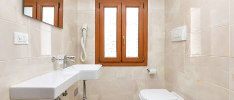 A modern bathroom with a white sink, a toilet, and a mirror.