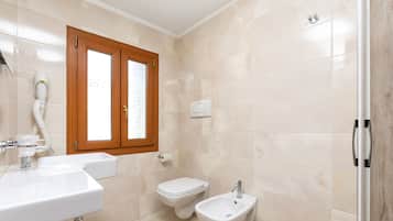 A bathroom with a sink, bidet, and bidet seat.