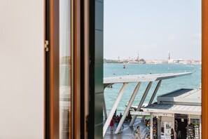 Blick auf ein Ufergebiet mit einer modernen Brücke, einem Boot im Wasser und einem Gebäude mit dem Schild "BA".