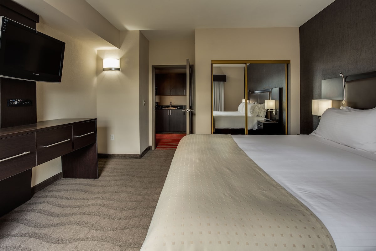 Relax in this spacious room featuring a large bed, flat-screen TV, and desk with drawers.
