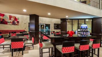 A restaurant with high tables and chairs, a bar area, and a view of the kitchen.