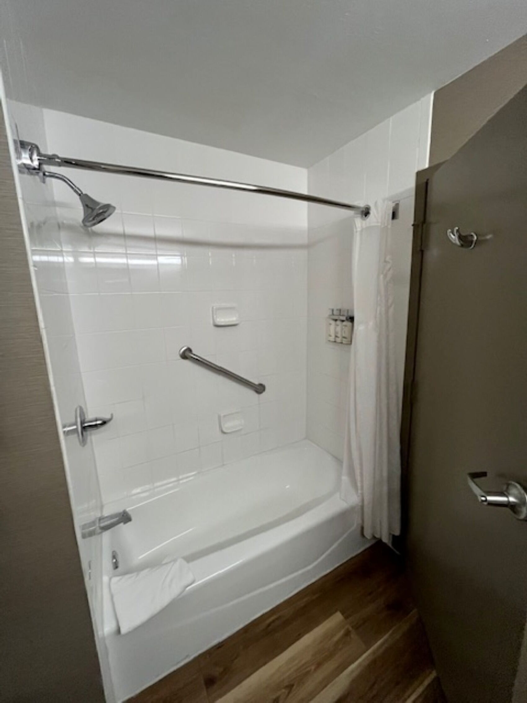 A bathroom with a shower, a bathtub, and a door.