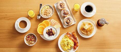 Ett frukostbord med olika rätter, inklusive pannkakor, ägg och bakverk.