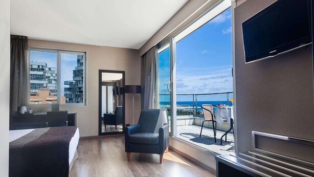 A modern hotel room with a bed, a chair, a desk, and a TV. - Hotel Best Front Maritim (Barcelona)