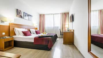 Una habitación de hotel con una cama grande, mesitas de noche, un escritorio y una televisión.