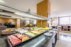 Un bufé con diversos alimentos y una zona de estar con mesas y sillas.