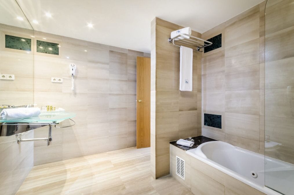 Un bagno moderno con doccia vetro, vasca freestanding e mobile vanità in vetro con articoli da toilette.
