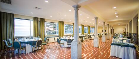 A spacious banquet hall with multiple round tables, chairs, and a patterned floor.