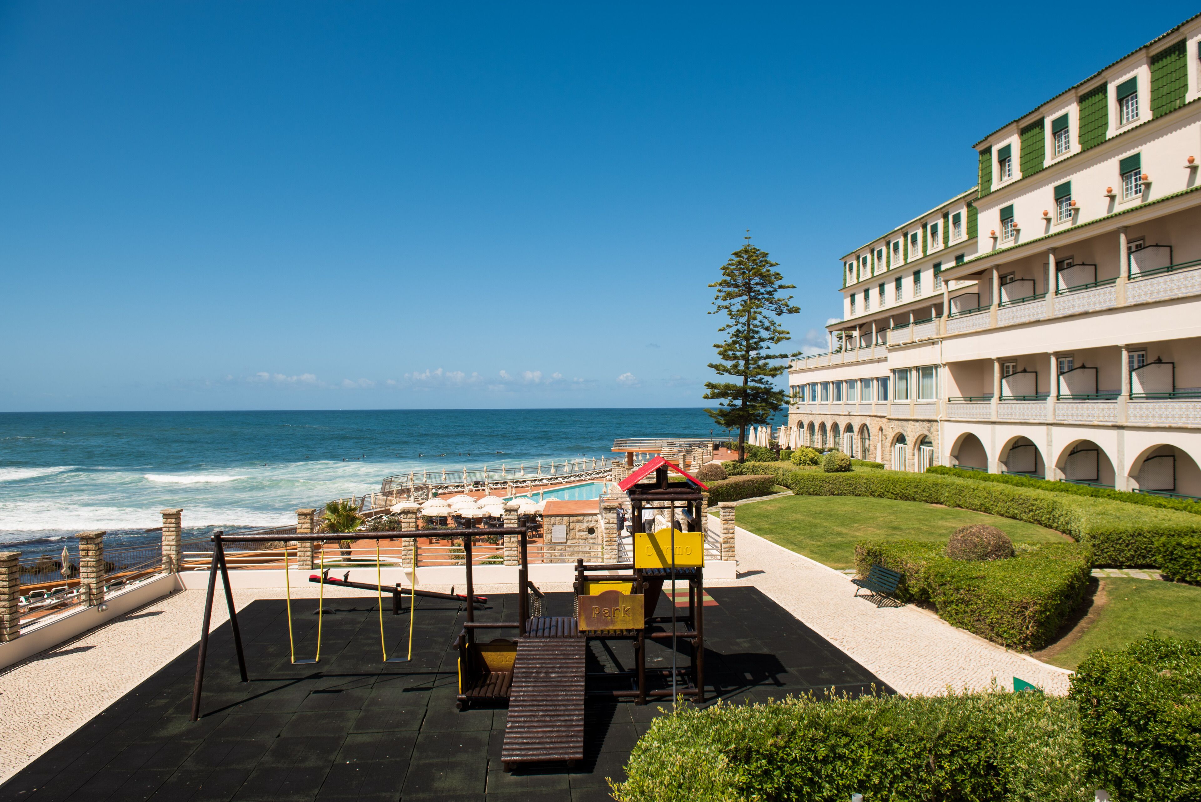 Un hotel frente a la playa con piscina, parque infantil y vista al océano.