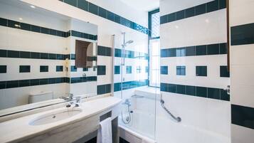 A modern bathroom with a large sink, mirror, and a glass-enclosed shower area.