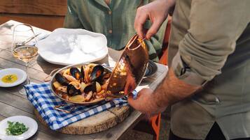 Una mesa de comedor con mariscos, una copa de vino y una olla de cobre.