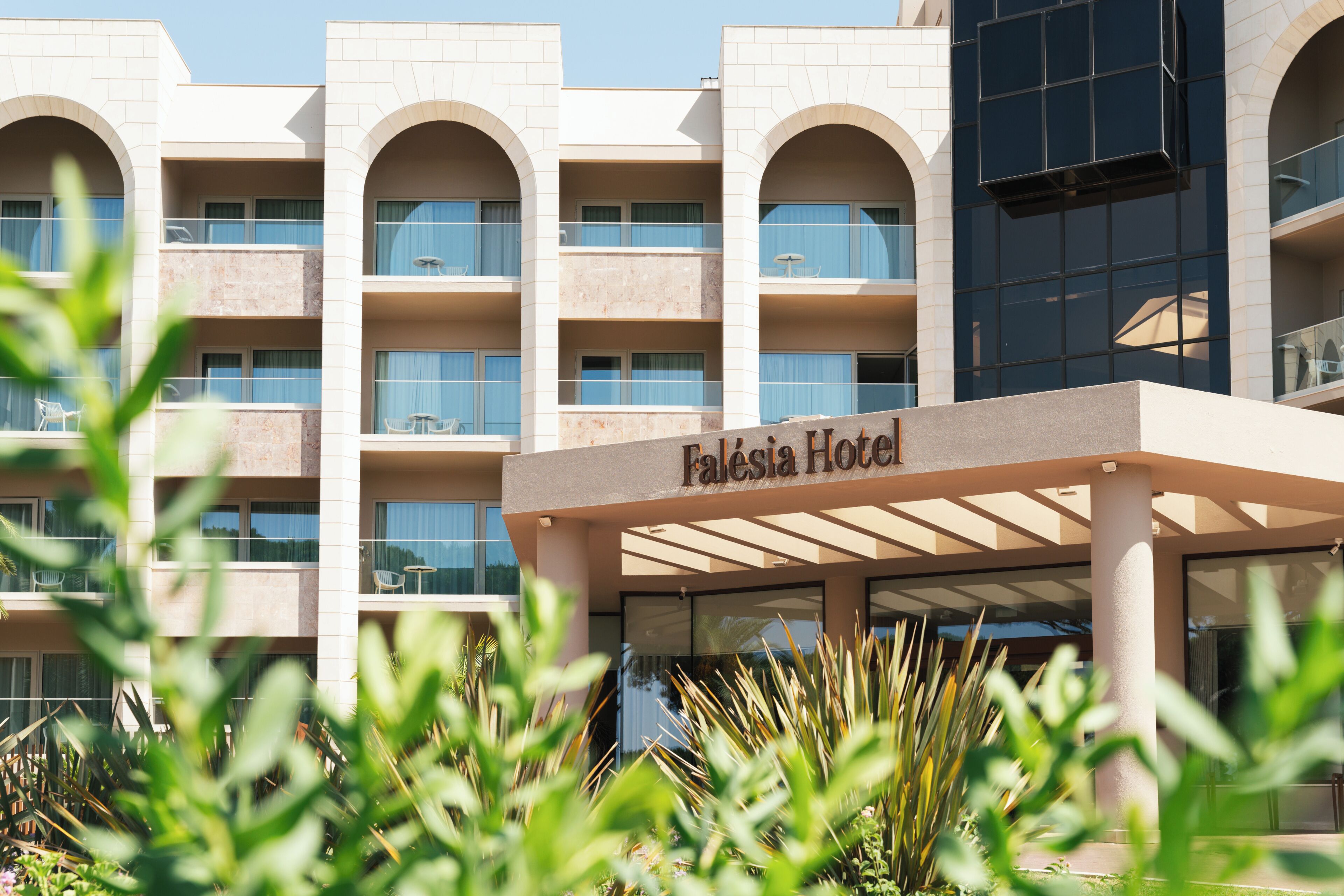 Un hotel con un diseño arquitectónico moderno, que cuenta con varios balcones y una señalización clara que dice 'Falesia Hotel'.