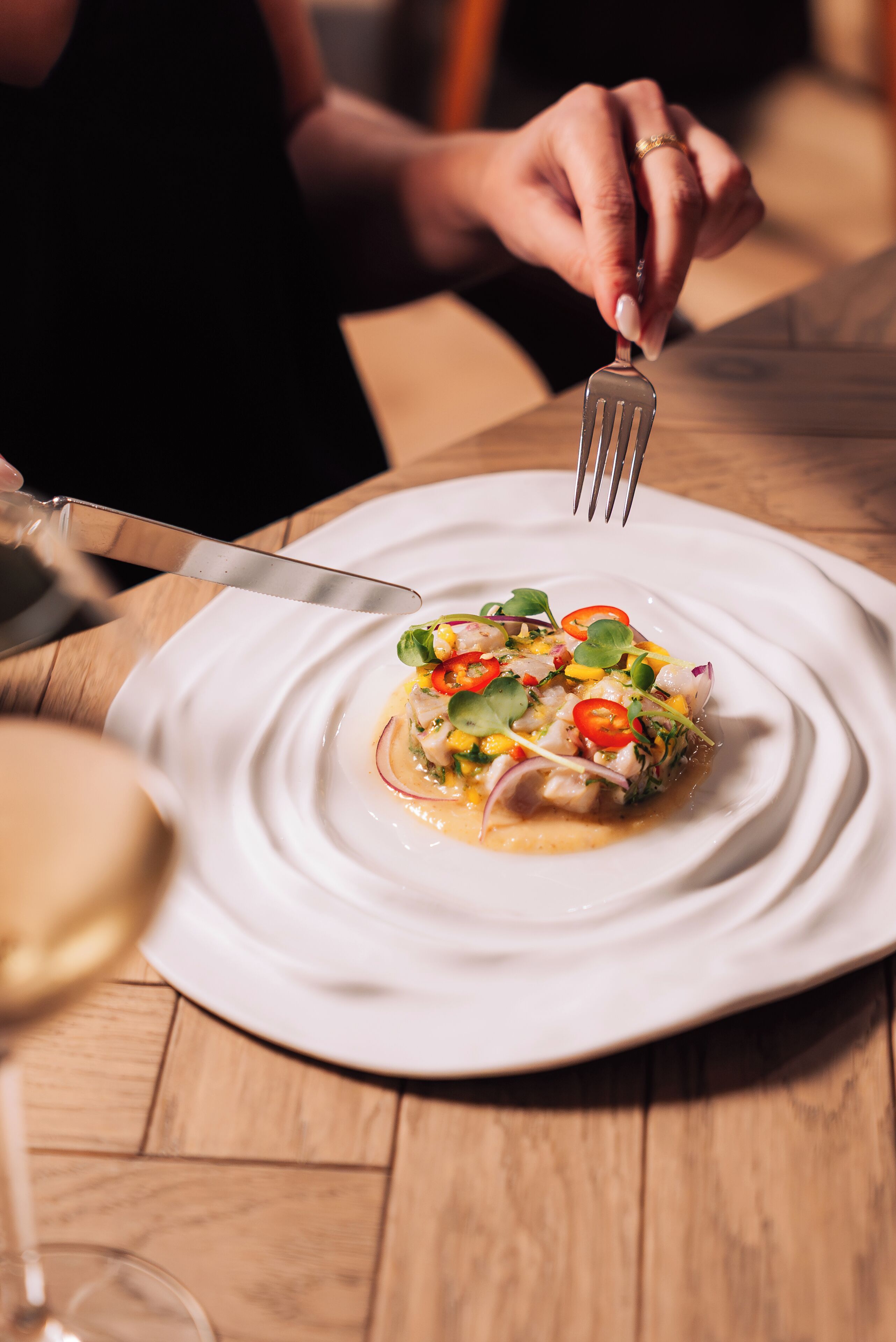 A person cutting a dish on a white plate.