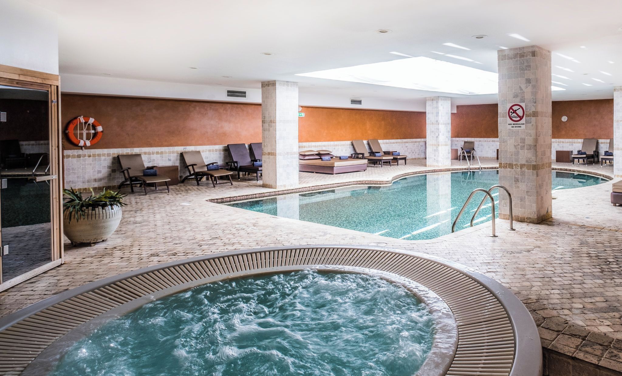 Une piscine intérieure dotée de chaises longues et d’un jacuzzi.