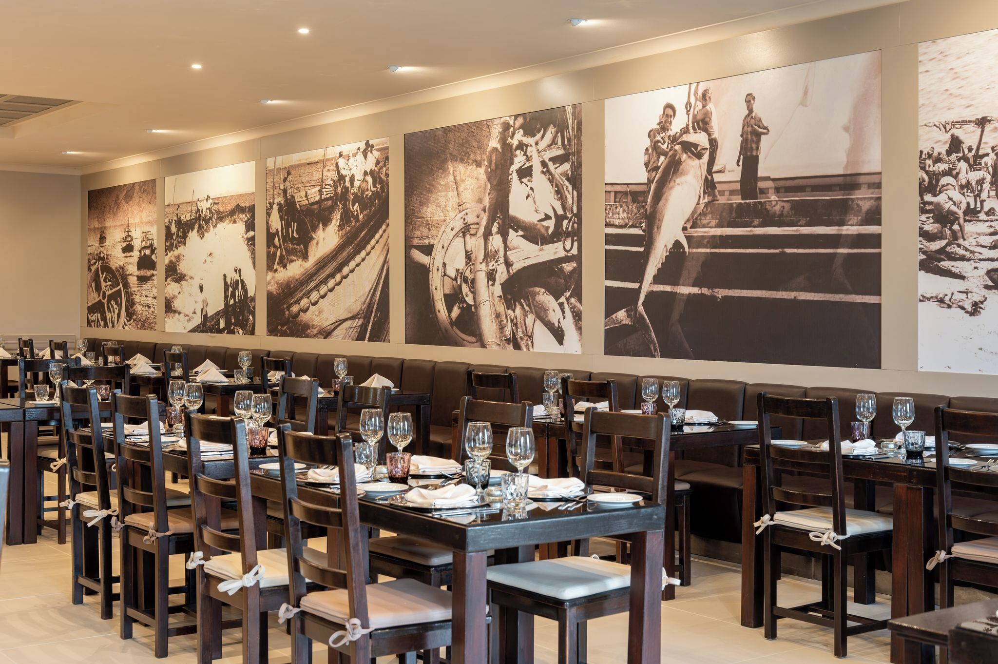 A restaurant with multiple dining tables, chairs, and a wall adorned with large black-and-white photographs.