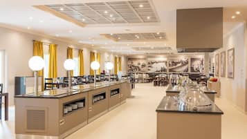 Une cuisine moderne dotée d’un îlot central, de luminaires suspendus et d’un coin repas avec chaises et tables.