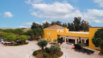 A yellow building with a sign reading 'VILA GALÉ ALBACORA,' a paved courtyard with trees, and parked bicycles.