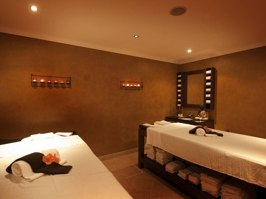 A hotel room with two beds, a large mirror, and a wall-mounted light fixture.