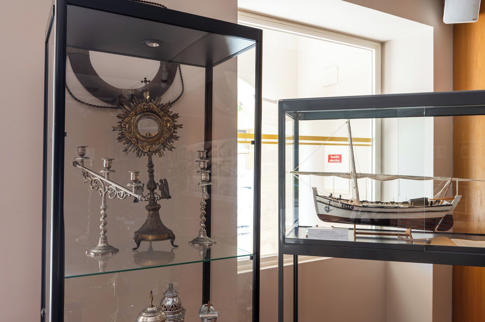 Una vitrina con un modelo de barco y candelabros de plata ornamentados.