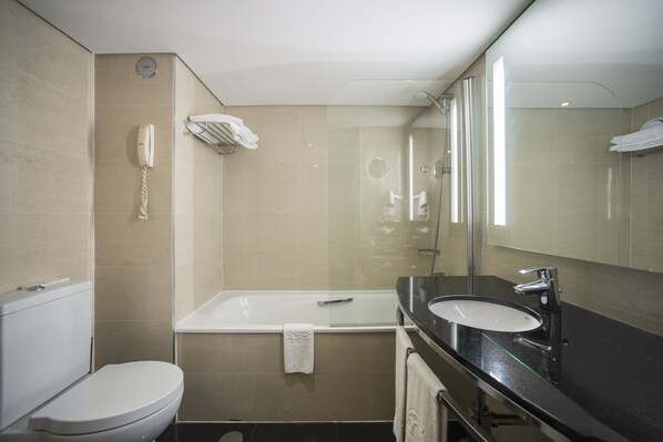 Un baño moderno con inodoro, bañera, lavamanos y un espejo grande.