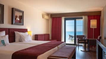 Habitación de hotel con una cama grande, un escritorio, una silla y vista al mar.