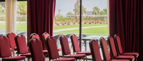 Rows of red chairs with metal frames arranged in a conference room with large windows.