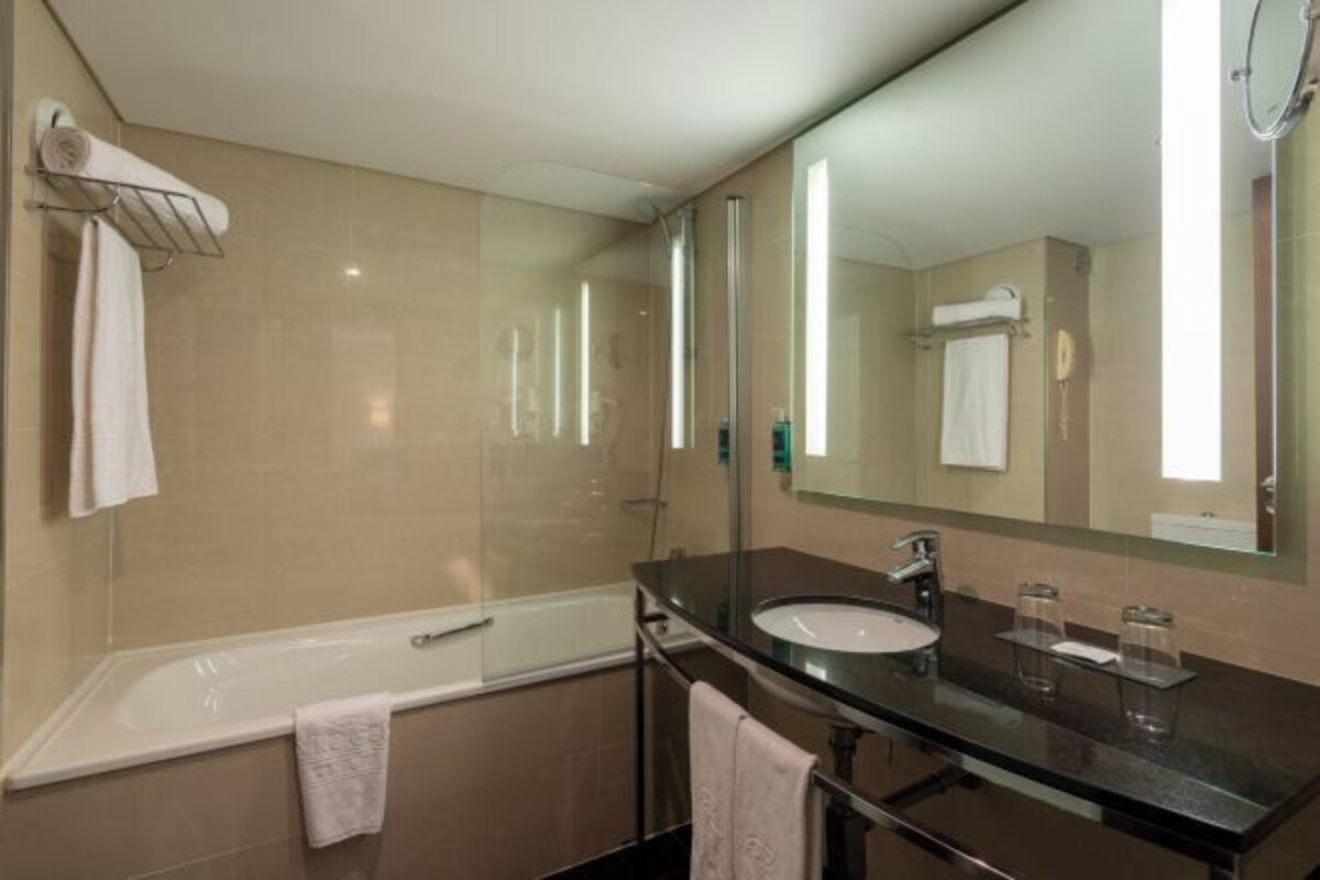 Un baño moderno con una bañera, un lavabo y un espejo grande.