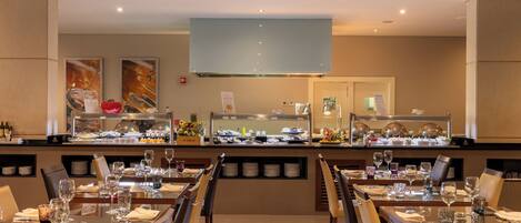 A restaurant with multiple dining tables, chairs, and a buffet area with various food items.