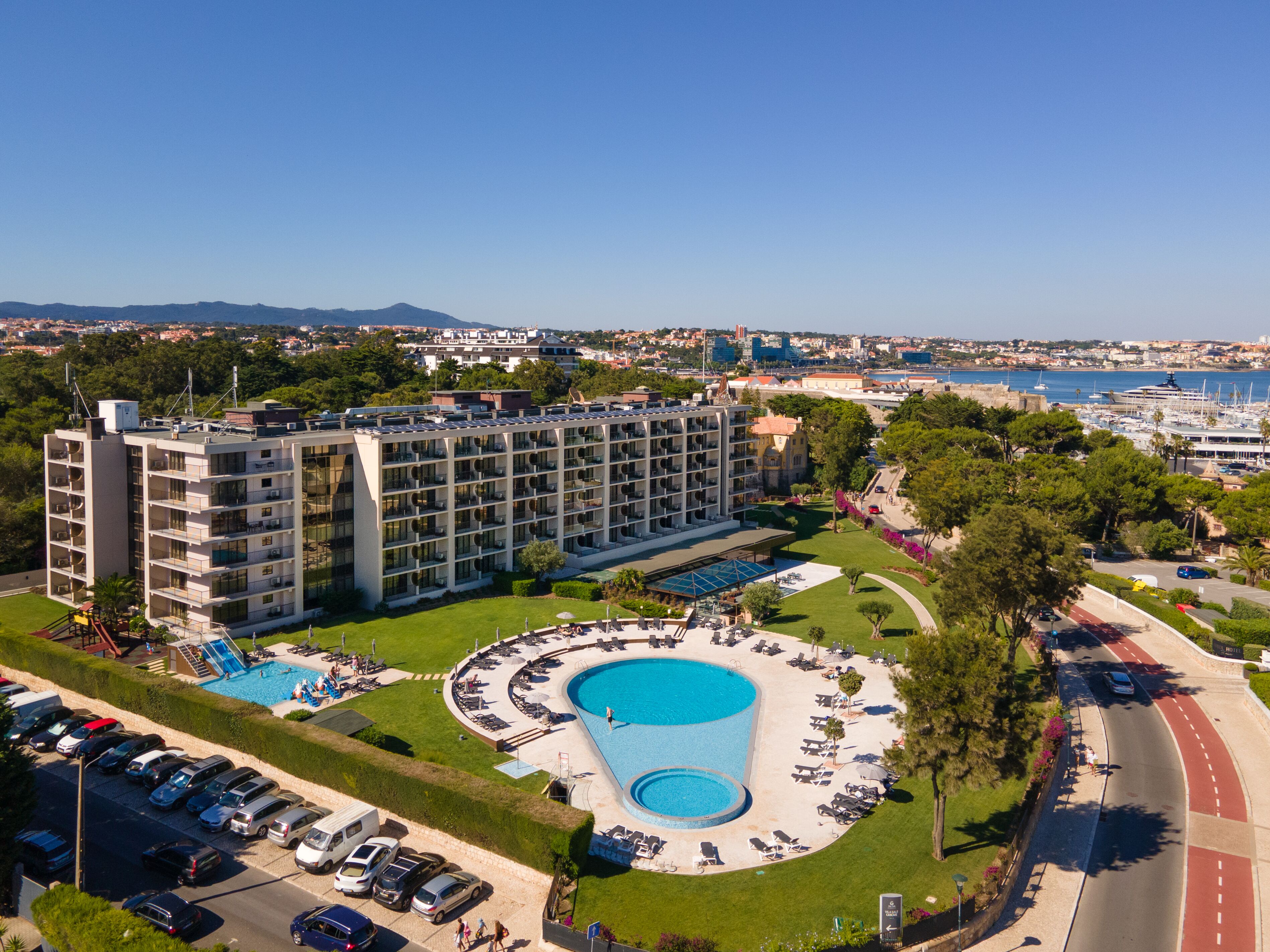 Um hotel com piscina, vários andares e vista para o mar.