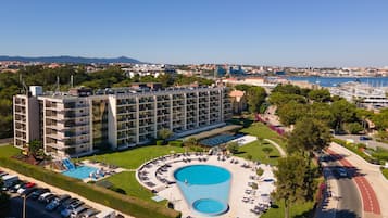 Um hotel com piscina, vários andares e vista para o mar.