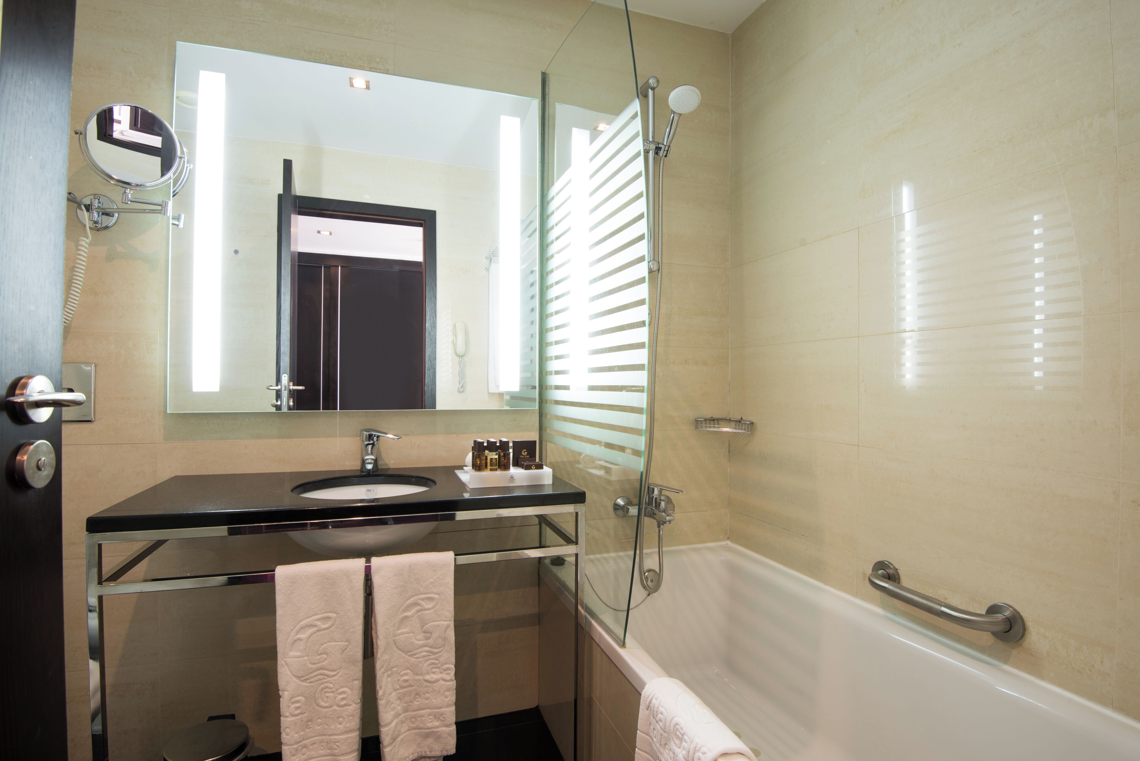 A bathroom with a glass-enclosed shower, a sink with a mirror above, and a towel rack with towels.