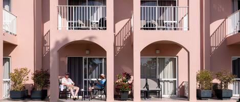 A building with multiple balconies, outdoor seating, and potted plants.