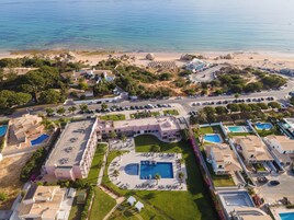 Vista aérea de um resort com várias piscinas, uma praia e um estacionamento.