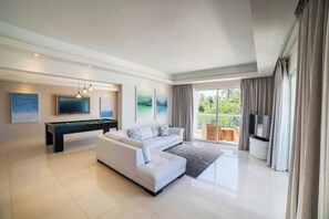 Relax in this stylish living room with a large sofa, pool table, and flat-screen TV.