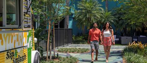 A couple walking on a pathway with a food truck parked on the side.