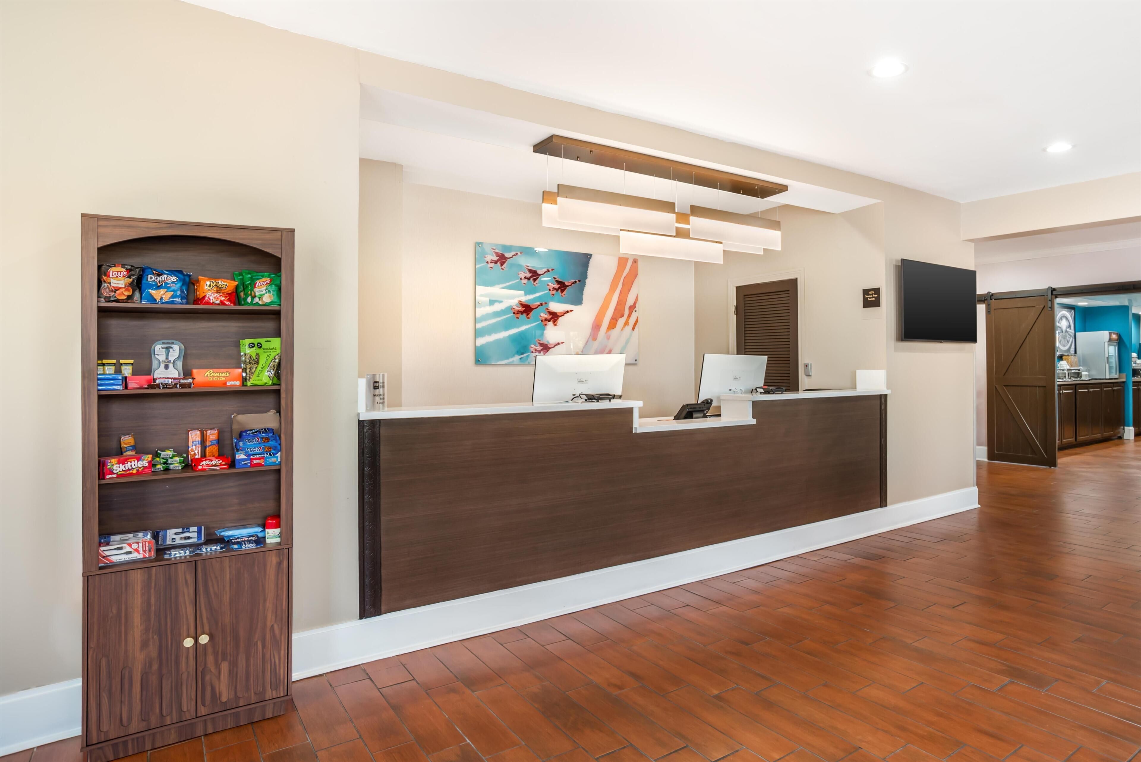 A reception desk with a wooden cabinet to the left, a painting above it, and a television on the wall.