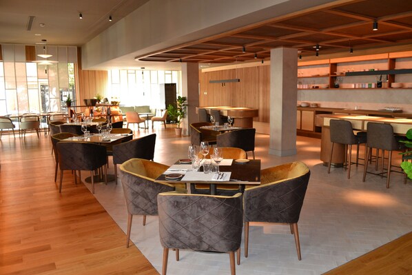 Un restaurante espacioso con varias zonas de comedor, suelo de madera y muebles modernos.