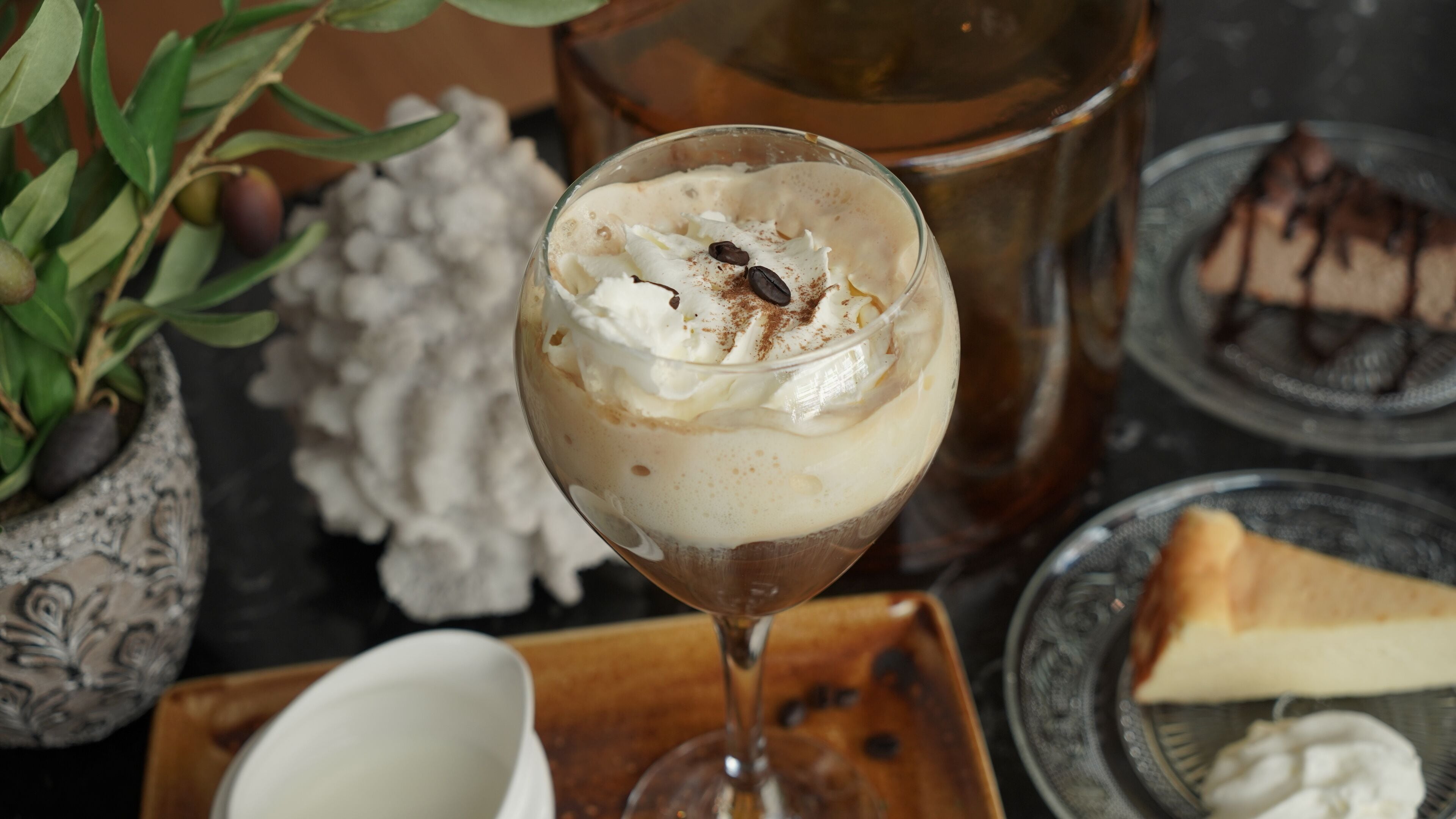 Un dessert servi dans un verre, composé de crème fouettée, de pépites de chocolat et d’une pincée de cannelle.