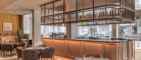 A modern bar area with a curved counter, seating with cushioned chairs, and a view of the street outside.