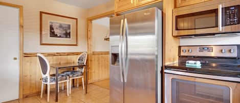 A kitchen with wooden cabinets, a stainless steel refrigerator, a microwave, and an oven.