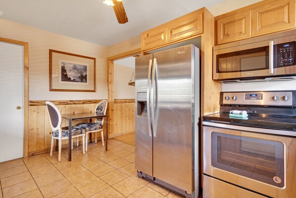 A kitchen with wooden cabinets, a stainless steel refrigerator, a microwave, and an oven. - 3 Peaks Resort & Beach Club (South Lake Tahoe)