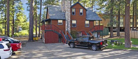 A two-story building with a stone chimney, wooden siding, and a red staircase leading to the upper level.